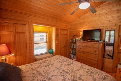 a bedroom with a bed and a flat screen tv at Cabin at Cranberry Mill - Private Creekfront Cabin in Laurel Springs 