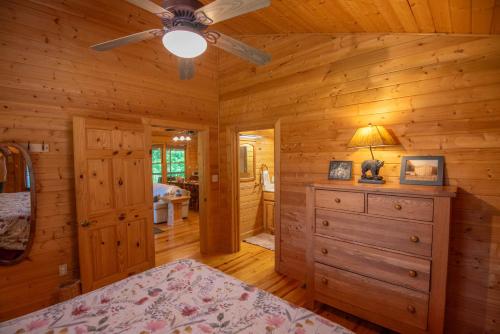 a bedroom in a log cabin with a bed and a ceiling fan at Cabin at Cranberry Mill - Private Creekfront Cabin in Laurel Springs 