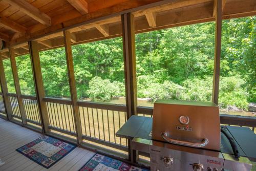 a screened in porch with a grill in the middle at Cabin at Cranberry Mill - Private Creekfront Cabin in Laurel Springs 