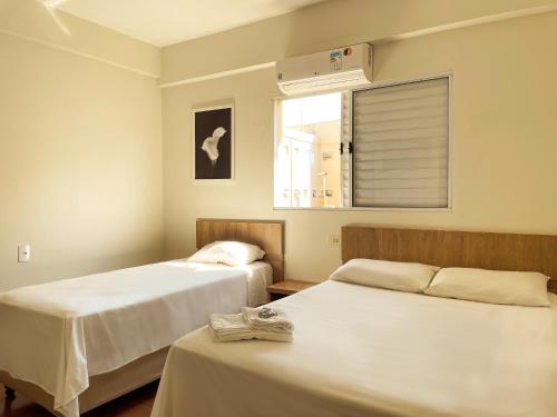 a room with two beds and a window with a fan at Lady Laura Hotel in Taquarituba