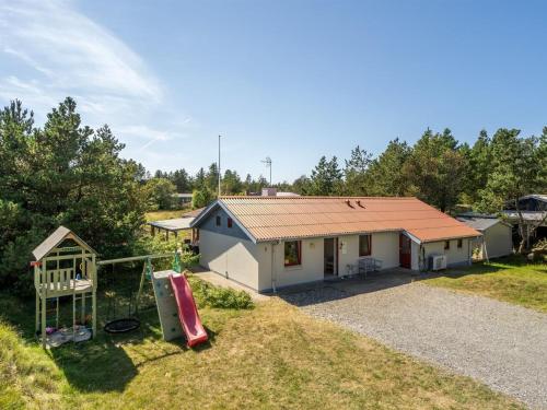 a small white house with a slide and a playground at Holiday Home Germund - 900m from the sea by Interhome in Torsted