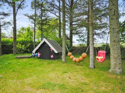 a small house in a yard with a chair and trees at Holiday Home Ludovic - 7km from the sea by Interhome in Thisted