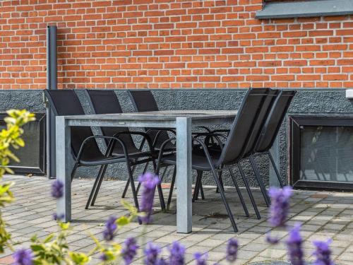 a table with four black chairs and purple flowers at Holiday Home Amely - 500m from the sea by Interhome in Sæby