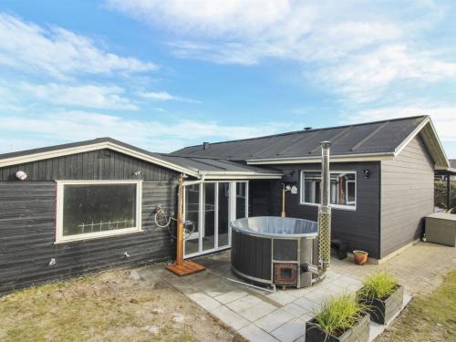 a black house with a hot tub on a patio at Holiday Home Jespar - 300m from the sea by Interhome in Løkken
