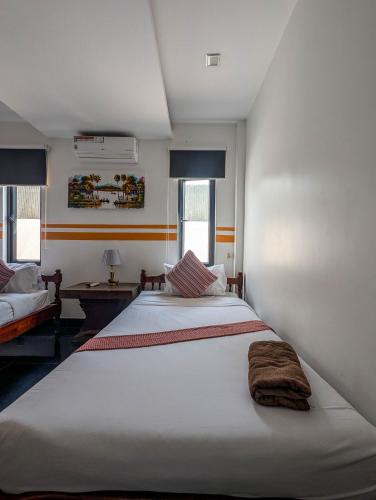 a bedroom with a large white bed and two windows at Travellers Inn in Phumĭ Réach Born