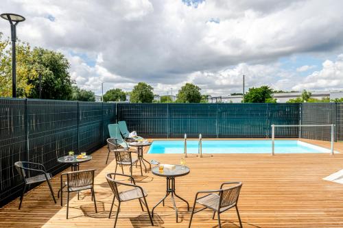 a patio with tables and chairs next to a pool at ibis Bordeaux Nord Carbon Blanc in Carbon-Blanc