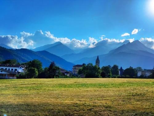 a field with a town and mountains in the background at Il Faro - Coazze in Coazze