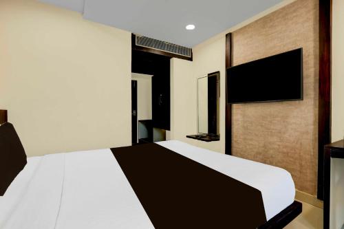 a bedroom with a white bed and a flat screen tv at Collection O Anu Hospital Elur Road in Vijayawāda