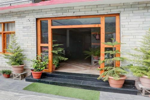 a front door of a house with potted plants at Hotel O Model Town Mall Road in Manāli