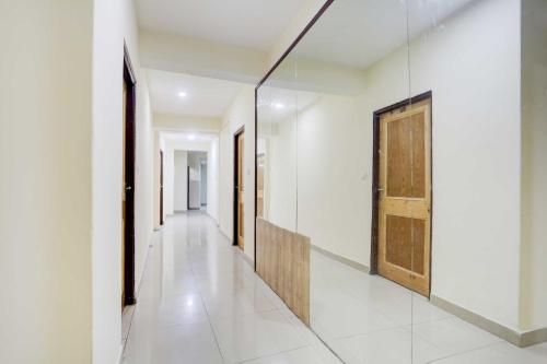 a hallway with white walls and a wooden door at Hotel O Model Town Mall Road in Manāli