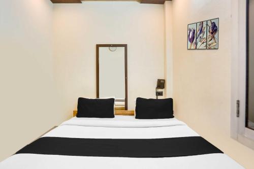a bedroom with a large white bed with black pillows at Collection O Jamrani in Haldwāni