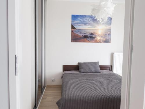 ein Bett in einem Zimmer mit einem Gemälde an der Wand in der Unterkunft Apartament Międzyzdroje Horyzont Blue in Misdroy