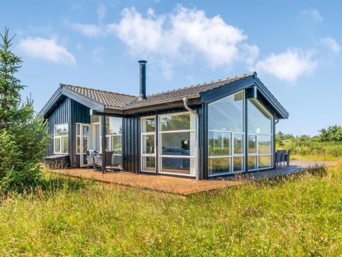 Una casa con grandes puertas de cristal en un campo. en Holiday Home Hildegardt - 1km from the sea by Interhome, en Løkken
