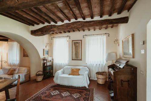 a living room with a white couch and a piano at Agriturismo Le Macchie in Monticchiello