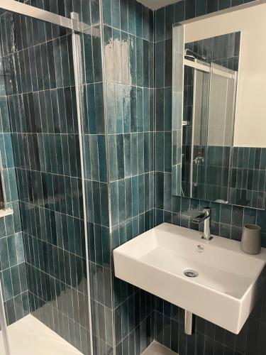 a green tiled bathroom with a sink and a mirror at Vivic Home Monforte in Monforte dʼAlba