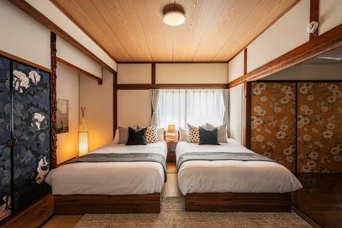 two beds in a room with a window at 阿蘇あそび バーベキューオプション 便利な立地 スーパーやレストラン充実 貸切 内牧温泉 最大10名 in Aso