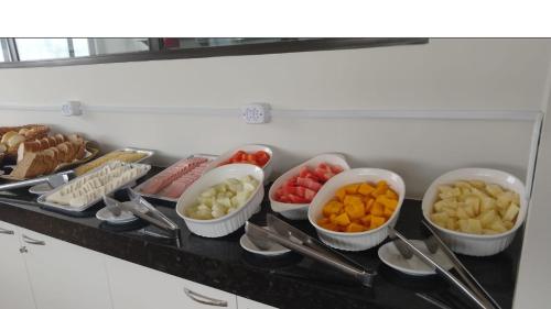 een bar met kommen van verschillende soorten voedsel bij ORA BEACH - Nidinho 1 in Porto De Galinhas