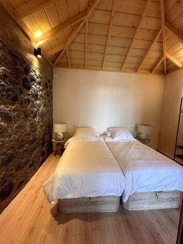 a large bed in a room with a stone wall at Casa Arriettas in Tijarafe