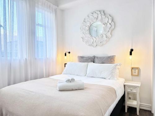 a bedroom with a white bed with a mirror on the wall at Central Queen St Stylish Penthouse 1BR Gem in Auckland