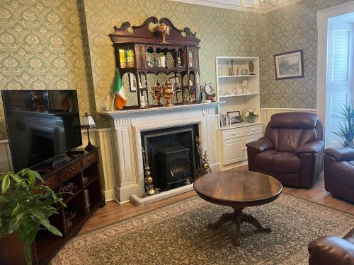 a living room with a fireplace and a chair and a table at Harbour House B&B in Courtown