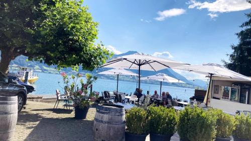 people sitting at tables under umbrellas near the water at Organic BnB Froschkoenig Rigi Burggeist in Gersau