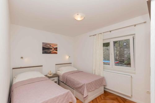 two beds in a room with a window at Villa Velaria with private pool in Donja Glavina