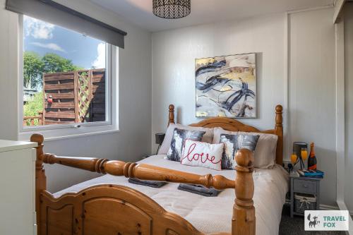 a bedroom with a wooden bed with pillows and a window at Lakeside Lodge in Caernarfon