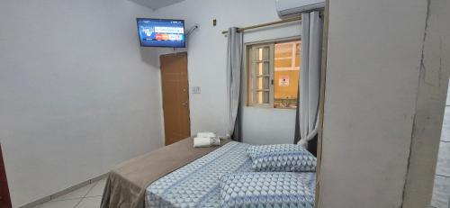 a bedroom with a bed with a television on the wall at Pousada Casa Verde in Aparecida