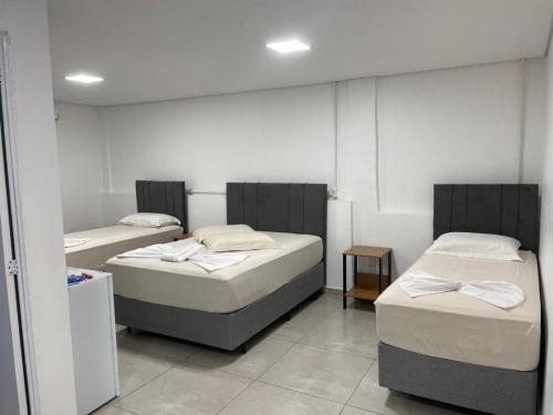 a room with three beds in a room at Hotel Califórnia Cruz Alta in Cruz Alta