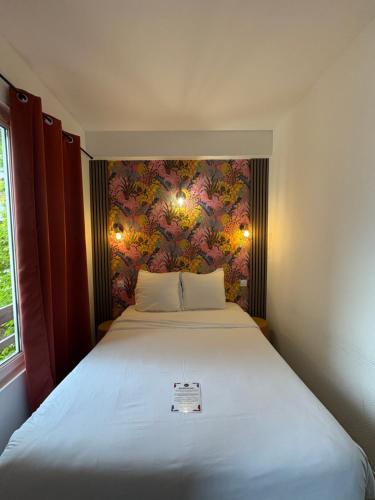 a bedroom with a large bed with a floral wall at Hotel Le Gambetta in Bergerac