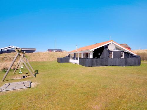 ein Haus auf einem Feld mit einem Teleskop in der Unterkunft Holiday Home Nedelko - 250m from the sea by Interhome in Blokhus