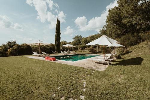 a swimming pool with umbrellas and chairs and a pool at Agriturismo Le Macchie in Monticchiello