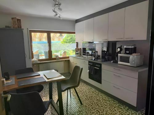 a kitchen with white cabinets and a table with chairs at Komfort trifft Natur in Albbruck