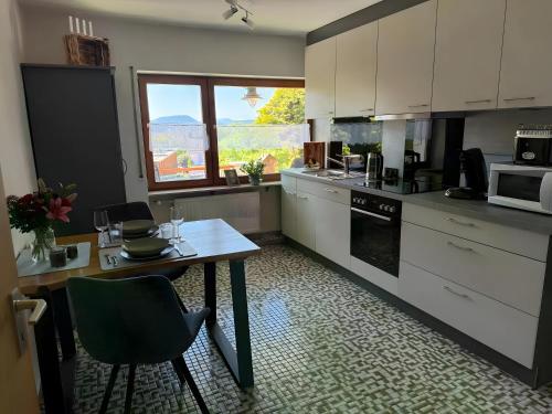 a kitchen with white cabinets and a table and a window at Komfort trifft Natur in Albbruck