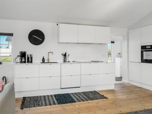 a kitchen with white cabinets and a clock on the wall at Holiday Home Wiebke - 200m from the sea by Interhome in Blokhus
