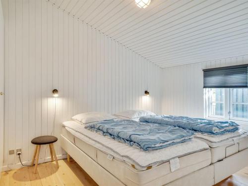 a white bedroom with a large bed with blue sheets at Holiday Home Wiebke - 200m from the sea by Interhome in Blokhus