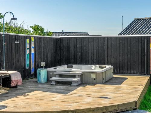 a hot tub on a wooden deck next to a fence at Holiday Home Wiebke - 200m from the sea by Interhome in Blokhus