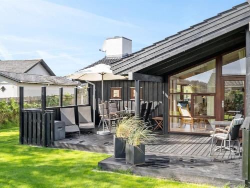 a house with a deck with chairs and tables at Holiday Home Friderike - 200m from the sea by Interhome in Blokhus