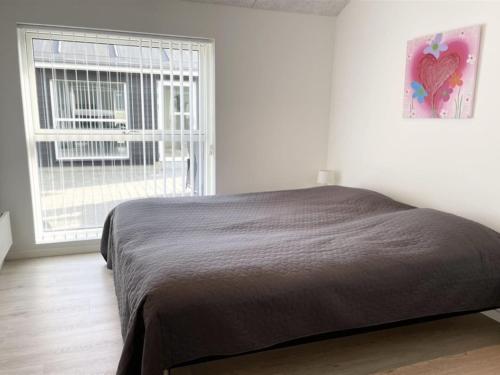 a bedroom with a bed and a large window at Holiday Home Dwerg - 1-5km from the sea by Interhome in Løkken