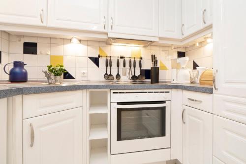 a white kitchen with white cabinets and appliances at Tannenburg Wohnung 205 in Grömitz