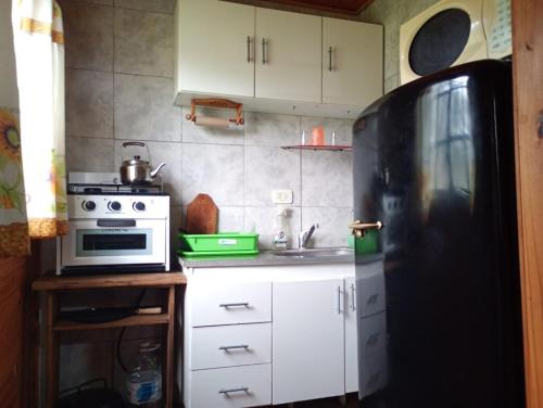 a kitchen with a black refrigerator and white cabinets at Pachaike in San Miguel del Monte