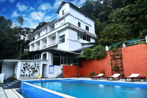 a building with a swimming pool in front of a building at Tree Blanche Resort Munnar in Anachal