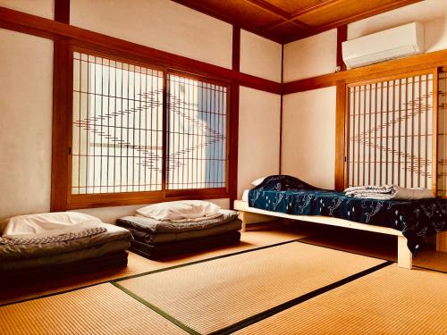 two beds sitting in a room with windows at 波止場の海まで徒歩30秒の宿ギョグンミニ"Gyogun Mini" in Ainan