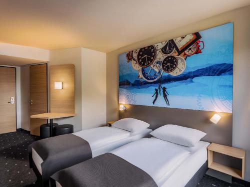 two beds in a room with a painting on the wall at B&B HOTEL Aalborg in Aalborg