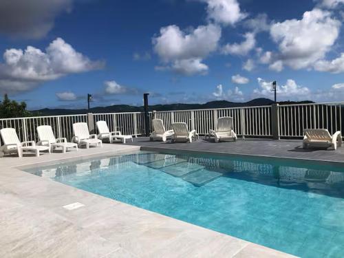 a swimming pool with lounge chairs at EDEN-RÉSIDENCE Le SAINT-BARTH Vue Mer et Piscine in Sainte-Luce