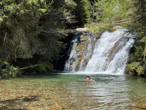 a man swimming in a river in front of a waterfall at Grand Lodge in Finhaut