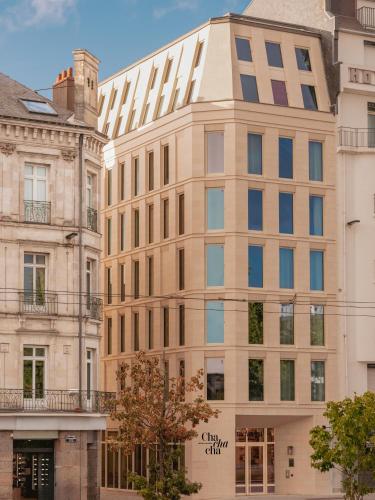 a tall building in front of two buildings at Chachacha Hôtel in Nantes