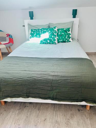 a bed with green pillows on it in a bedroom at la villa in Lacanau