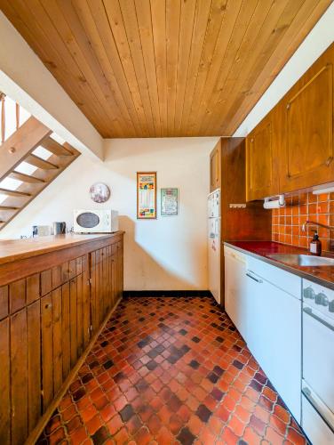 a kitchen with wooden cabinets and a tiled floor at Cœur de Champéry, terrasse & près des remontées ! in Champéry
