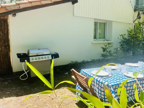 a picnic table with a grill in a backyard at la villa in Lacanau